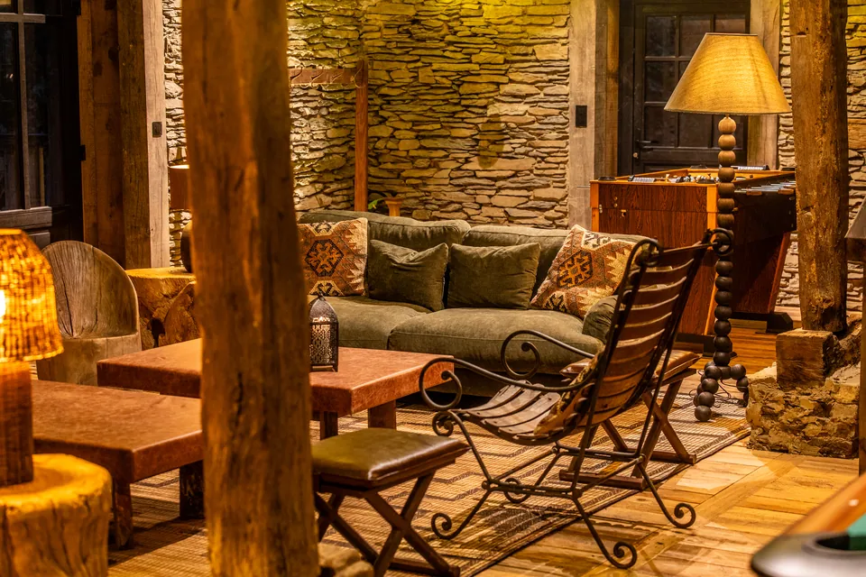 A warm shared lounge with timber beams, stone walls and seating