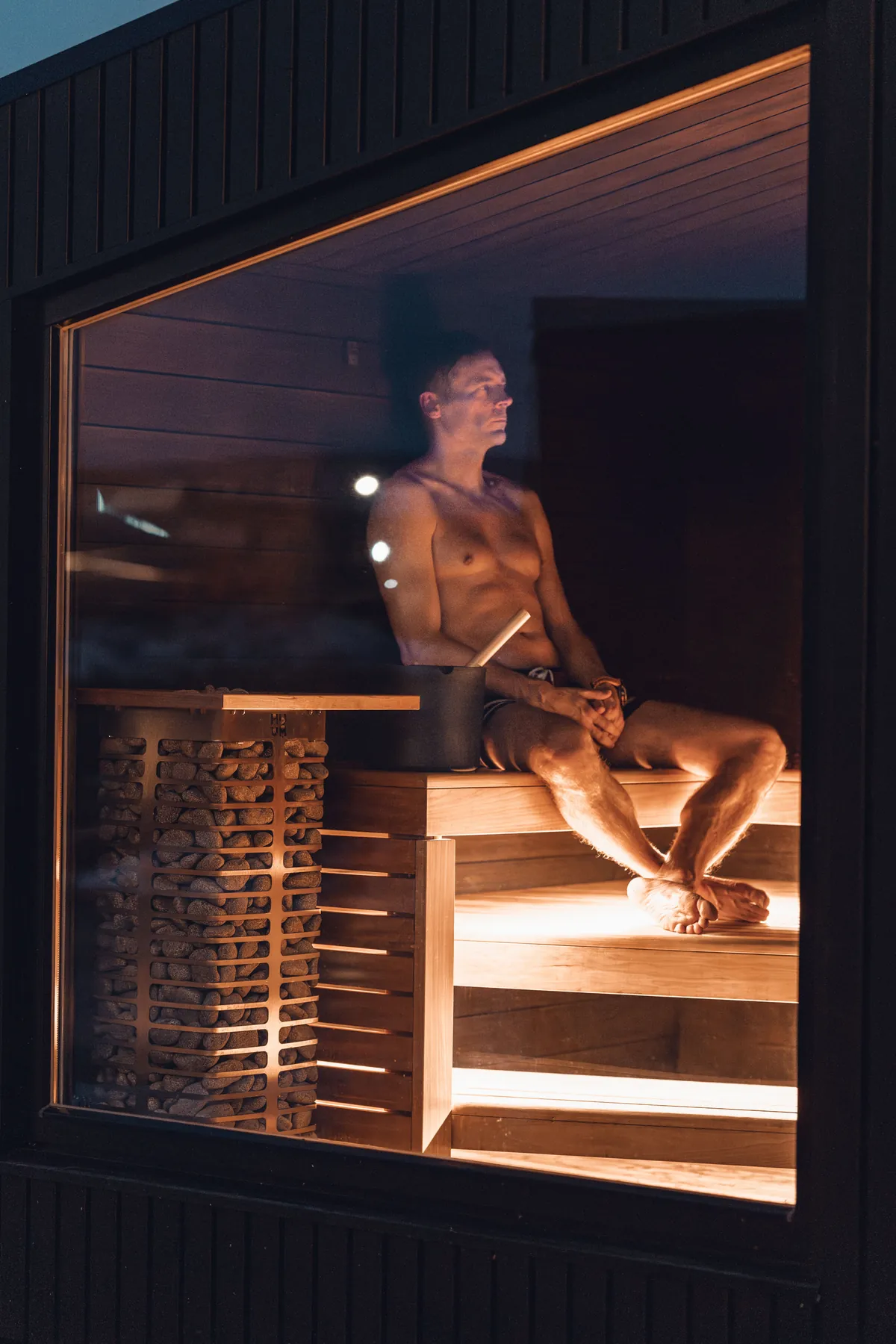 Person resting in a warmly lit wooden sauna
